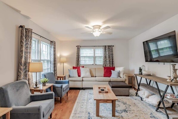 A living room with a sofa, armchairs, a coffee table, and a TV.