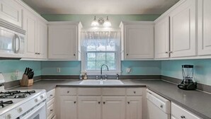 A kitchen with white cabinets, a sink, a stove, and a blender on the countertop. - Near Midtown, Highways, Downtown! Bel-Air Bungalow (Mobile)