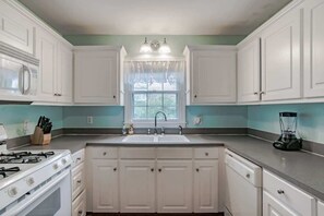 A kitchen with white cabinets, a sink, a stove, and a blender on the countertop. - Near Midtown, Highways, Downtown! Bel-Air Bungalow (Mobile)