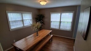 A room with a wooden dining table and benches, two windows with blinds, and a ceiling light fixture. - Near Midtown, Highways, Downtown! Bel-Air Bungalow (Mobile)