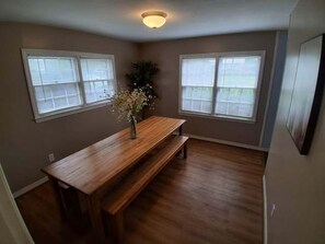 A room with a wooden dining table and benches, two windows with blinds, and a ceiling light fixture. - Near Midtown, Highways, Downtown! Bel-Air Bungalow (Mobile)