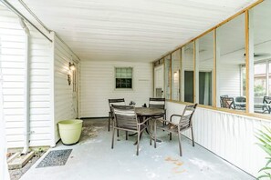 A covered patio with a table and chairs, a window, and a door. - Near Midtown, Highways, Downtown! Bel-Air Bungalow (Mobile)