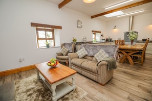 Un salon chaleureux avec une table basse en bois, un canapé à rayures et un coin repas comprenant une table et des chaises en bois.
