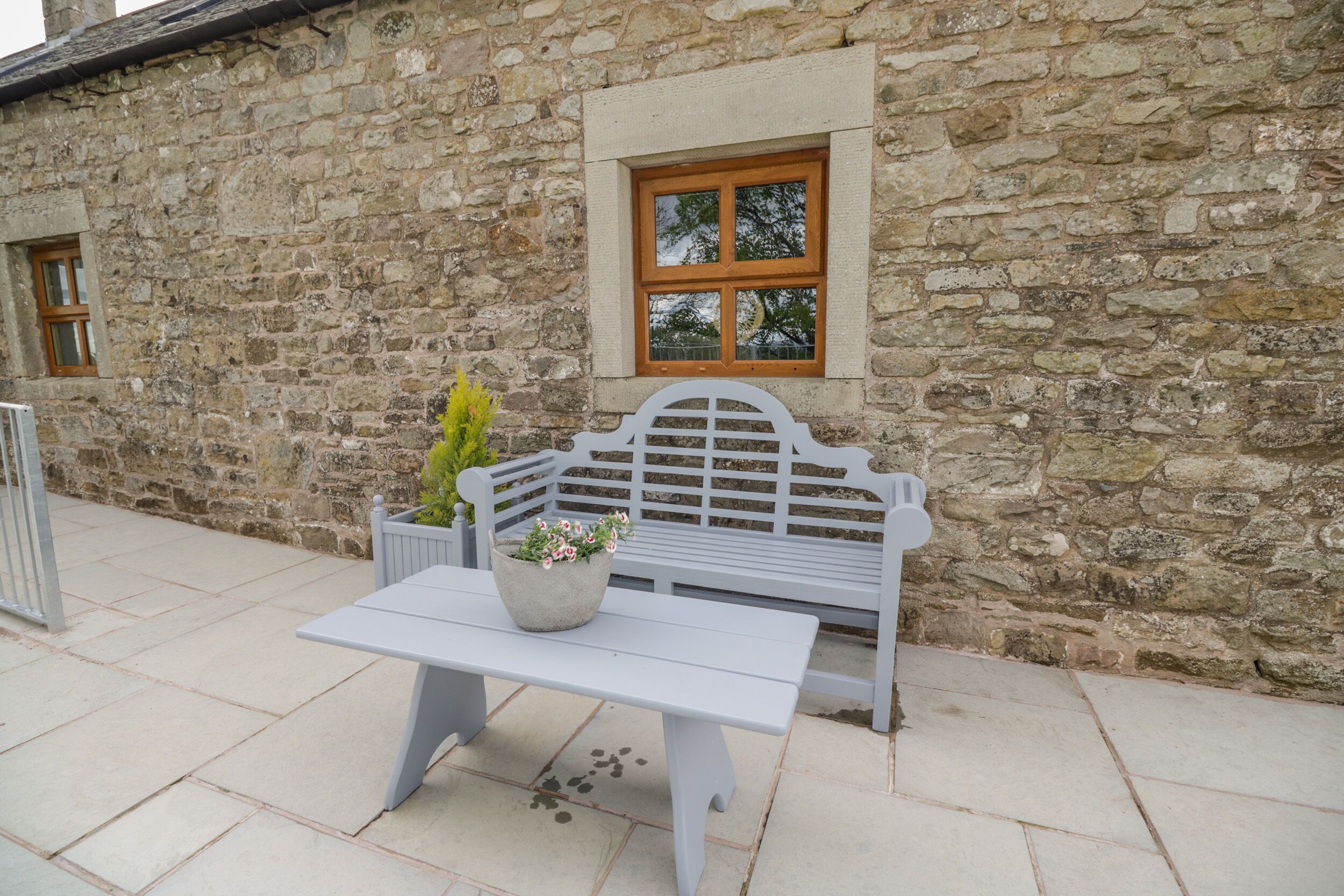 Een stenen gebouw met een bank en een tafel met een bloempot.