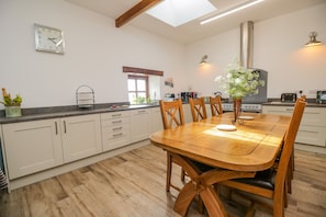 Une cuisine moderne avec une table à manger en bois, des placards blancs et un four encastré.