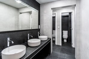 A modern bathroom with two sinks, a large mirror, and a toilet visible through an open door. - Hostel Center Madrid (Madrid)