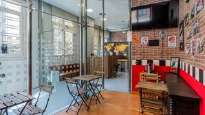 A modern cafe with a red counter, wooden tables, and a world map on the wall. - Hostel Center Madrid (Madrid)
