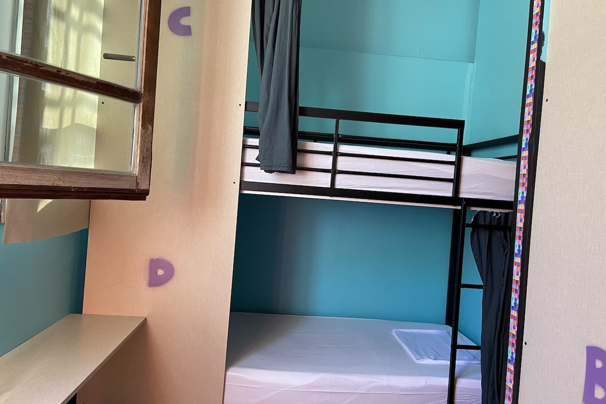 A bunk bed room with a window, a desk, and a door.