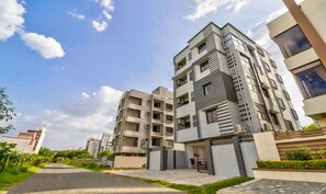 Un edificio residencial moderno con varios pisos, balcones y unidades de aire acondicionado.