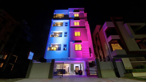 Un edificio de varios pisos con balcones y ventanas, que cuenta con una entrada protegida por un portón y un camino de entrada pavimentado.