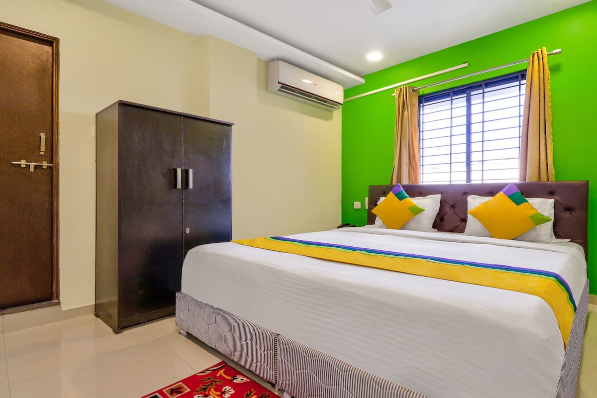 Une chambre à coucher comprenant un lit, une armoire, une fenêtre avec des rideaux et un appareil de climatisation.