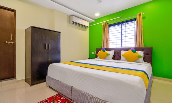 Un dormitorio con cama, armario, ventana con cortinas y equipo de aire acondicionado.