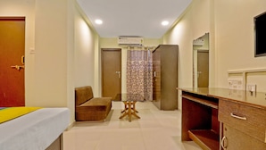 Una habitación de hotel con cama, sofá, mesita, espejo y cómoda.