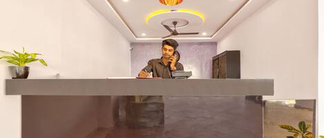A reception desk with a ceiling fan, a telephone, and a potted plant.
