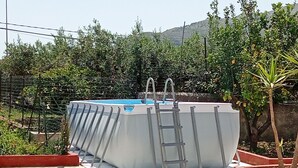 A swimming pool with a ladder, surrounded by a garden with various plants and a stone-tiled patio. - VILLA ROSA 2 - Antico Borgo Scopello NEAR THE SEA (Scopello)