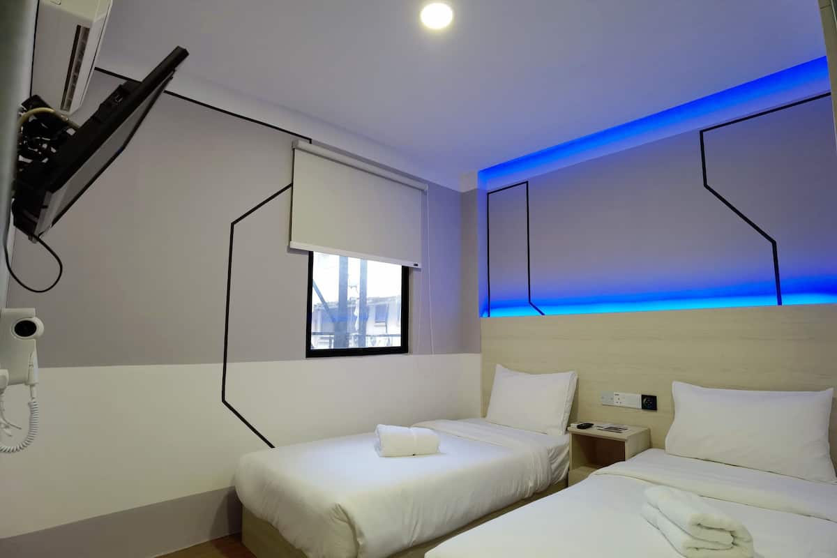 Ein Hotelzimmer mit zwei Betten, einem Föhn, einem Telefon und einem Fenster mit Blick.