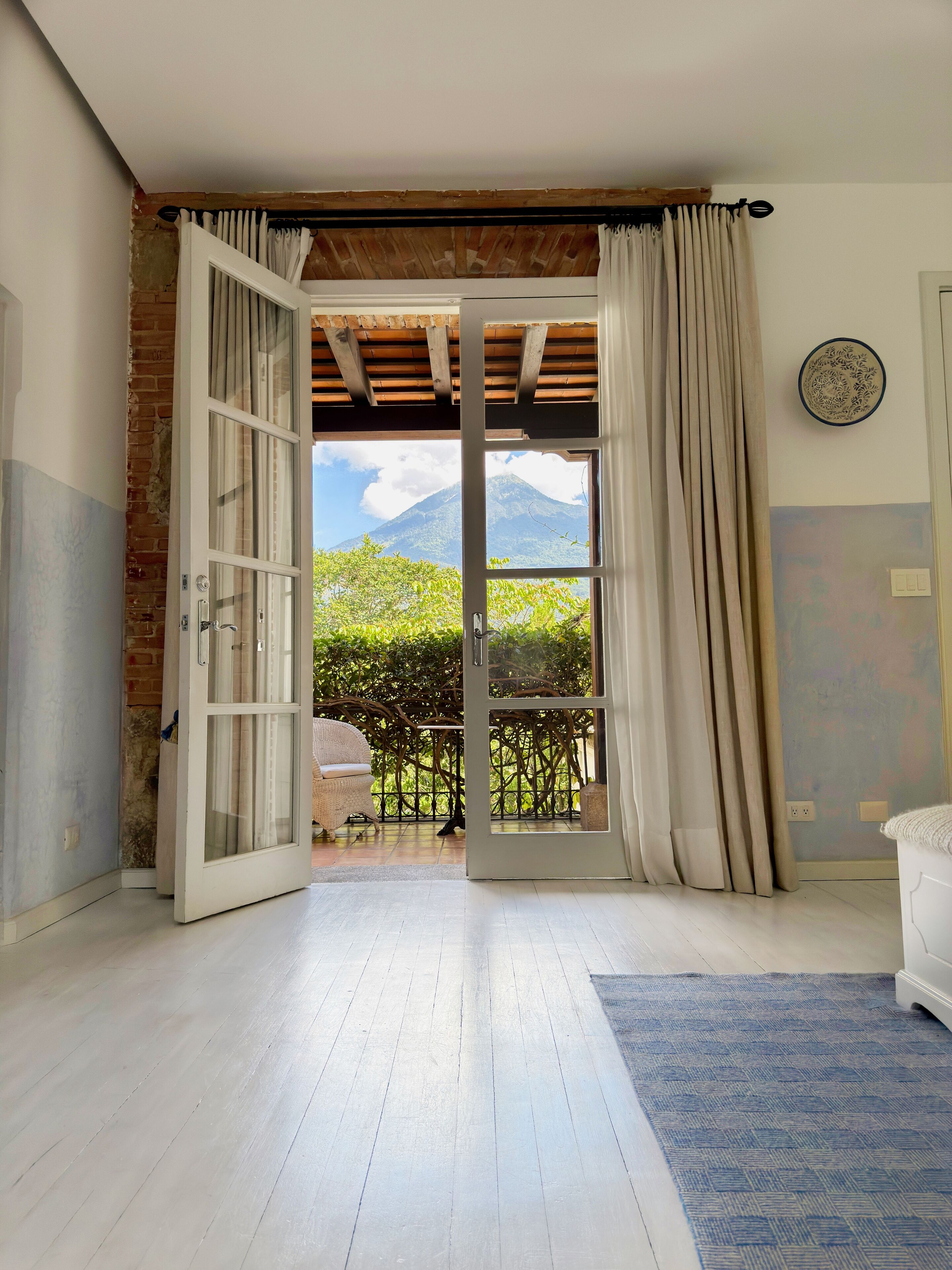 A room with a large sliding glass door leading to a balcony with a mountain view.