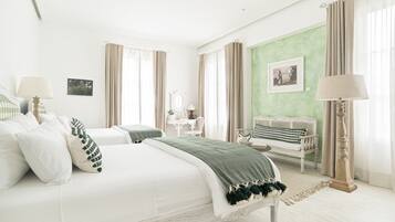 A spacious bedroom with a large bed, a sitting area with a bench, and a green accent wall.