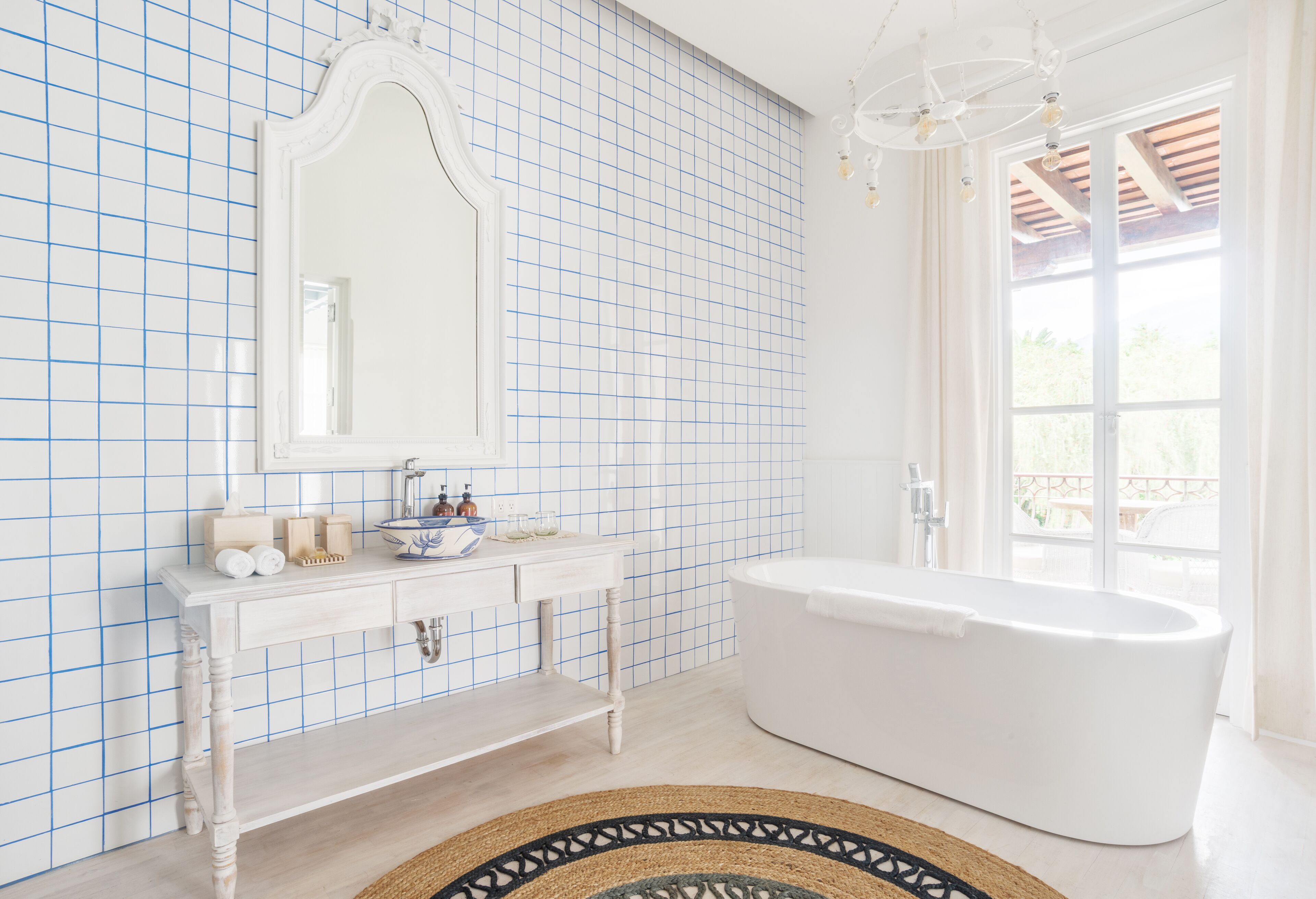 A bathroom with a white bathtub, a large mirror, and a tiled wall.