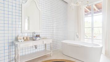 A bathroom with a white bathtub, a large mirror, and a tiled wall.