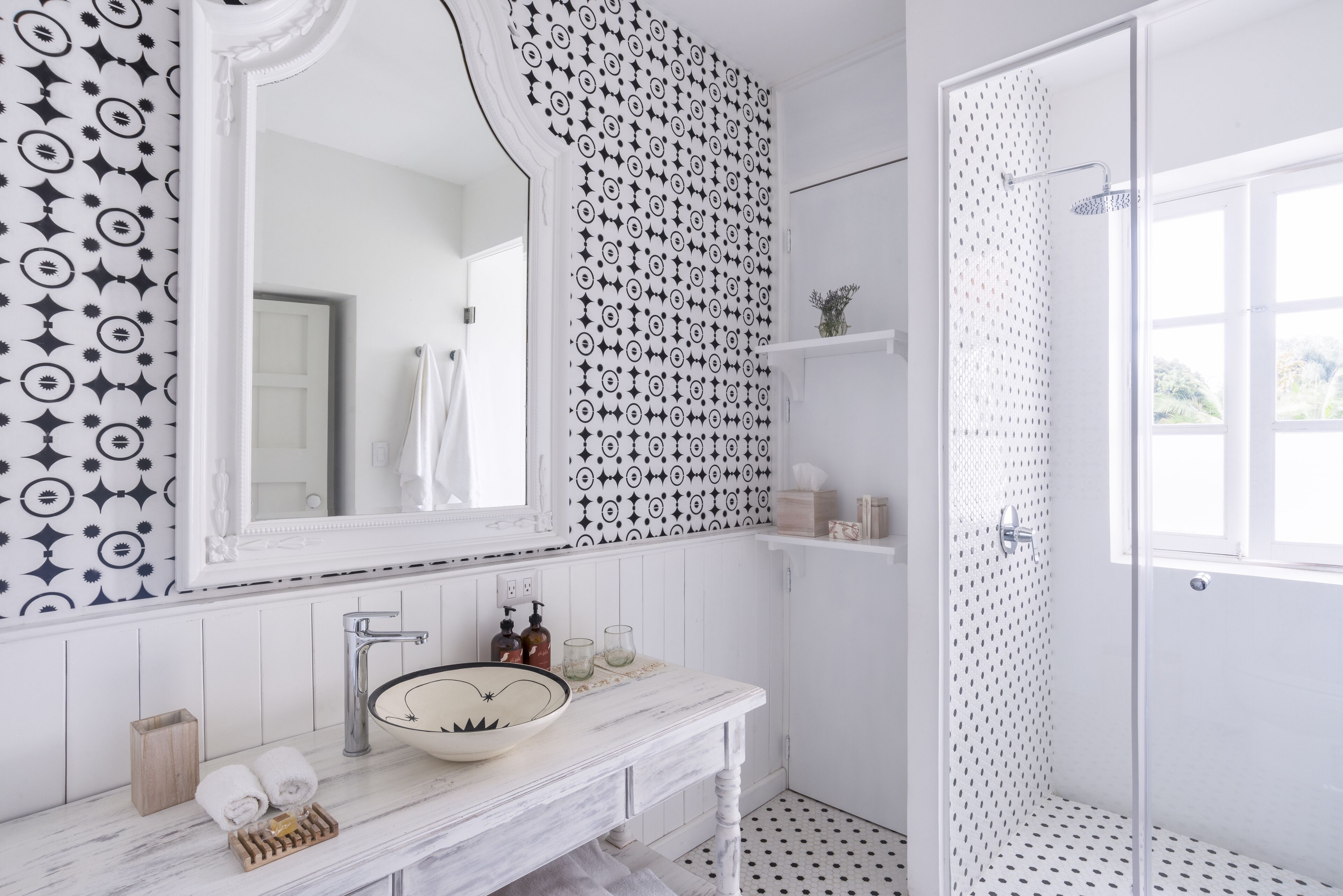 Une salle de bain avec un meuble-lavabo blanc, un grand miroir, un lavabo et un espace douche.