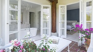 Un espacio habitable integrado con cocina, un baño con bañera y un dormitorio con cama y pared con diseño.