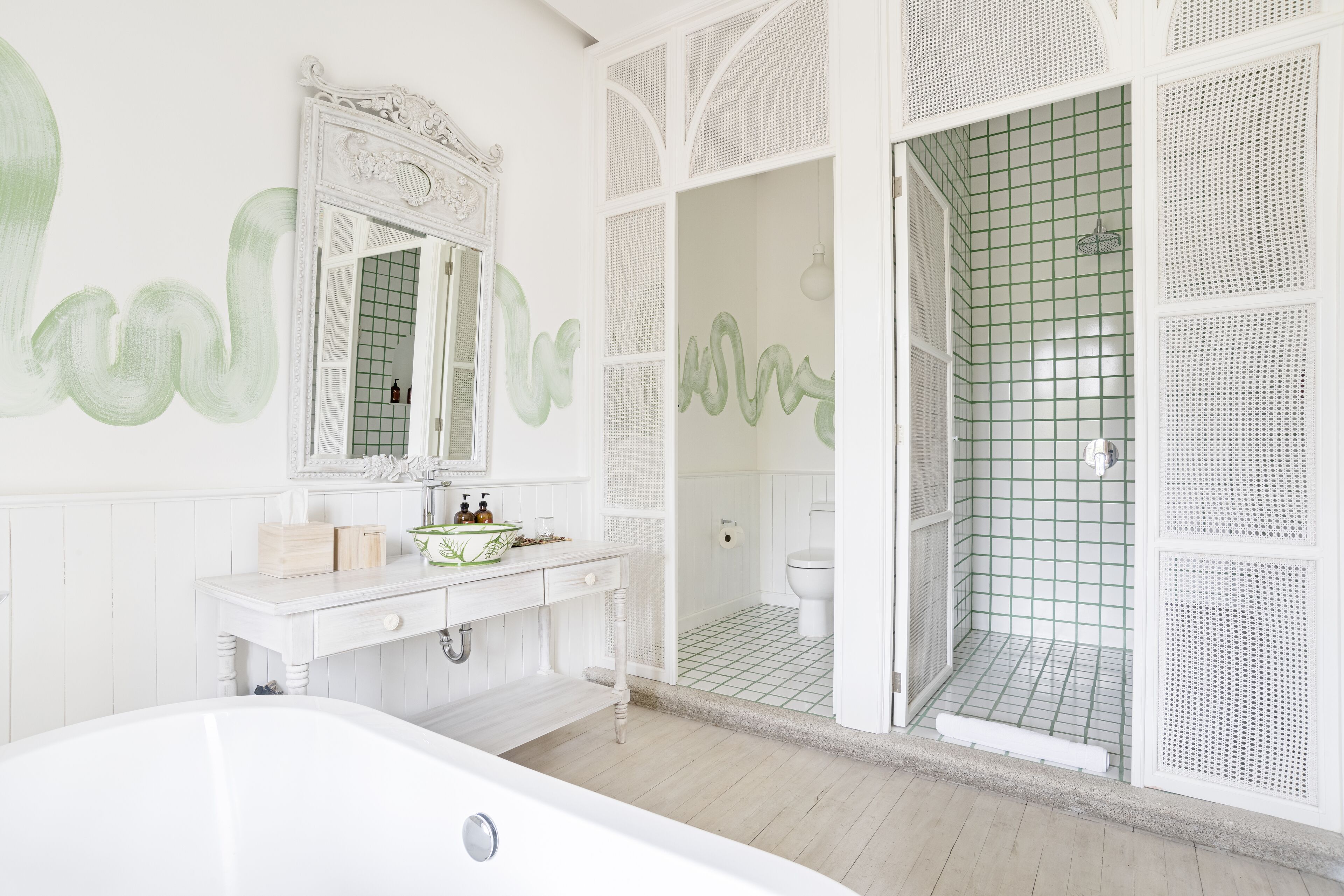 A bathroom with a white vanity, a large mirror, and a shower area with a grid-patterned wall.