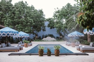 Una piscina al aire libre, sombrillas, sillones reclinables de piscina