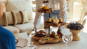 Una mesa de comedor con un plato de varios niveles, copas de vino y una planta en maceta.