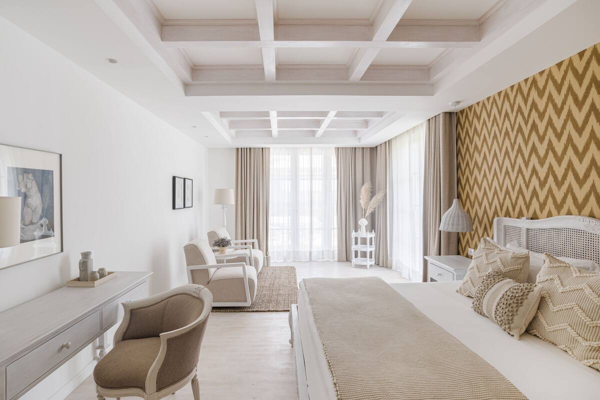 Quarto de hotel moderno com uma cama grande, uma escrivaninha, uma cadeira e uma mesa de cabeceira.