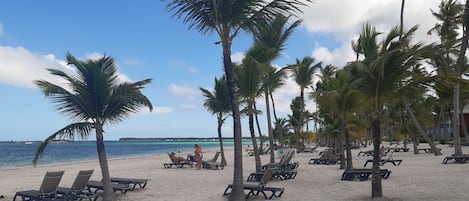 Na praia, espreguiçadeiras, toalhas de praia 