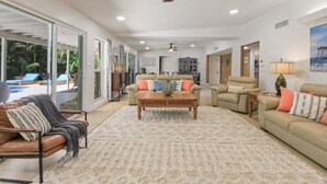 Ein geräumiger Wohnbereich mit einer großen Couch, einem Couchtisch und einem Deckenventilator.