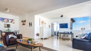 Een ruime woonkamer met een eettafel, banken en een keuken op de achtergrond.