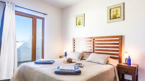 Een slaapkamer met een groot bed, twee nachtkastjes met lampen, een raam met gordijnen en twee ingelijste foto's aan de muur.