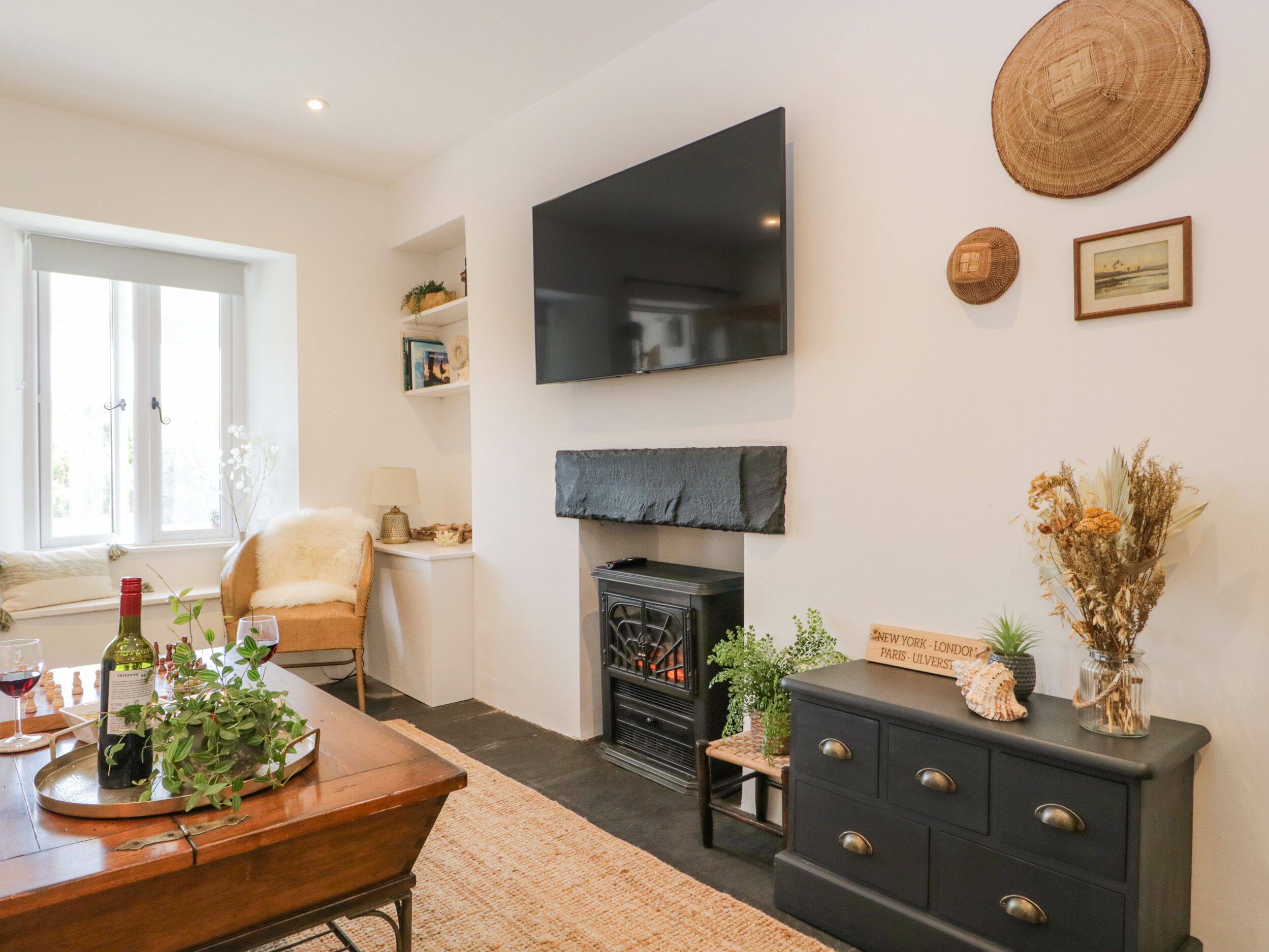 A living room with a fireplace, a television mounted on the wall, and a dining area with a table set for two.
