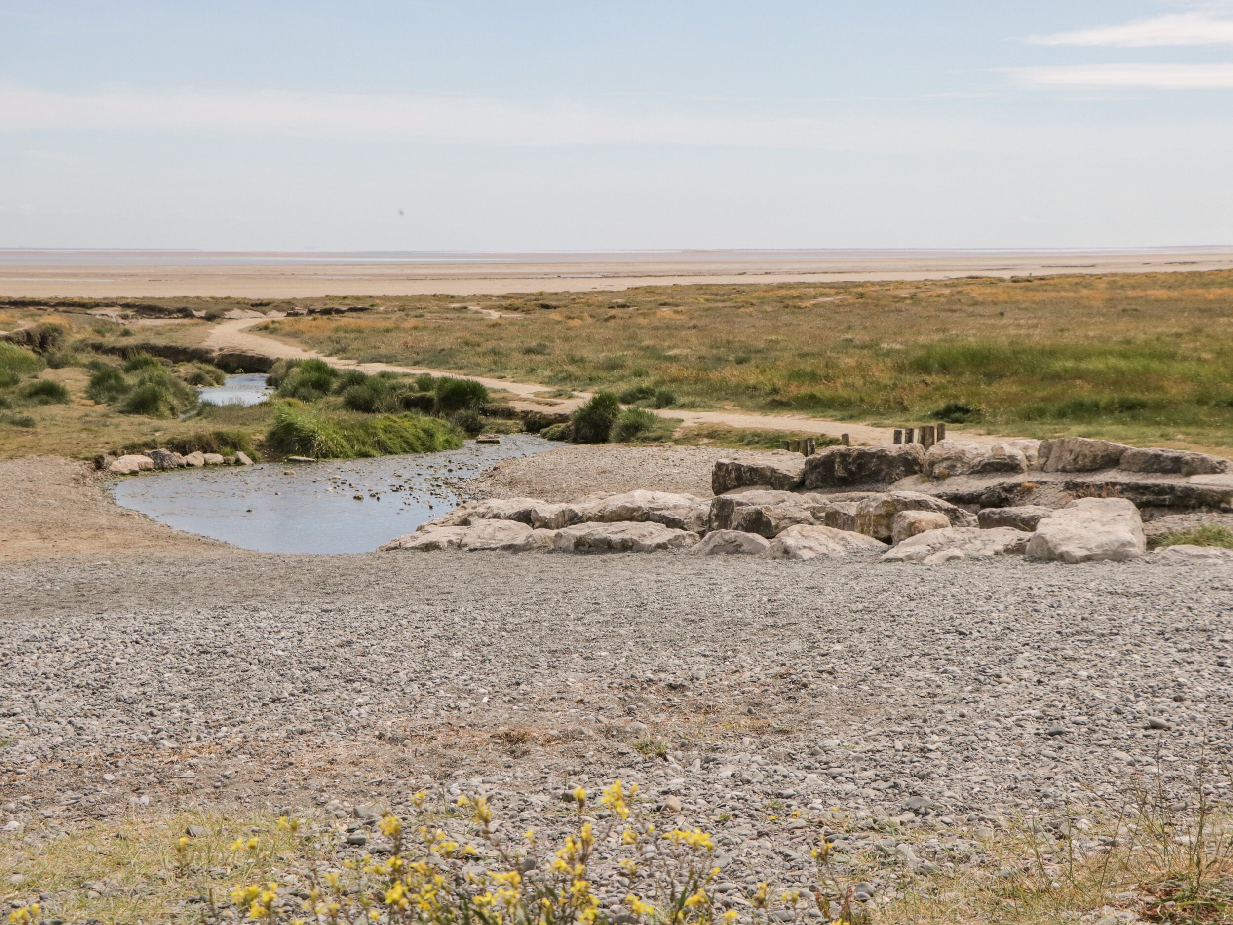 Un paysage aride et rocheux, avec un petit plan d’eau et une végétation clairsemée.