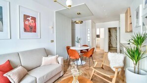 Uma sala de estar moderna com sofá, cadeiras, uma mesa de centro e um espaço de jantar com mesa e cadeiras.