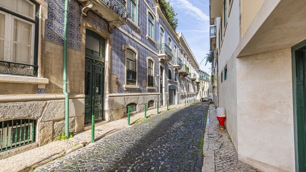 Eine enge Kopfsteinpflasterstraße, gesäumt von historischen Gebäuden mit aufwendigen Fassaden und traditionellen Balkonen.