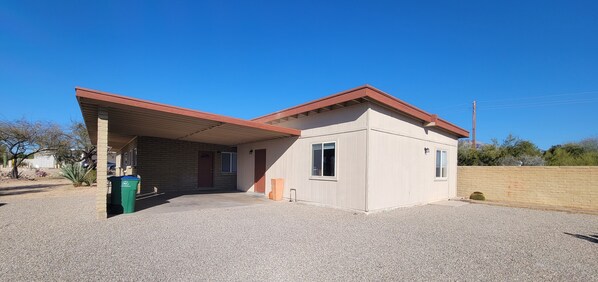A small, single-story building with a covered porch and a gravel driveway.