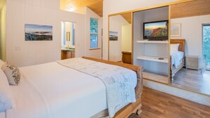 Une chambre à coucher avec un lit, un miroir, une télévision et une vue sur l’extérieur.