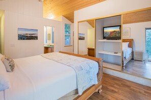 Ein Schlafzimmer mit Bett, Spiegel, Fernseher und Blick ins Freie.