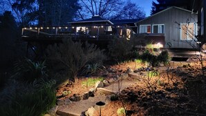 A house with a deck overlooking a garden at dusk.