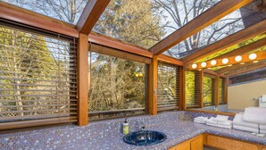 A bathroom with a mosaic tile floor, wooden beams, and a sink with towels.