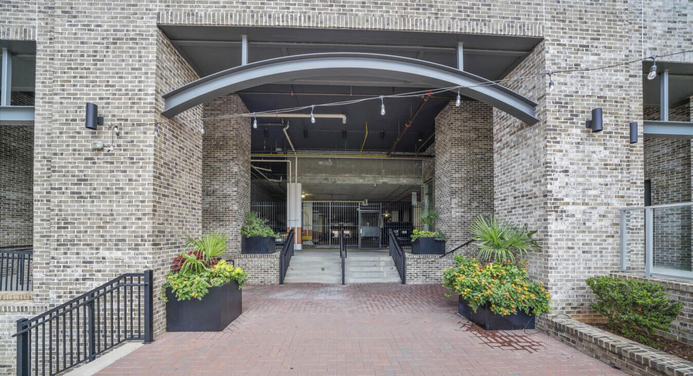 A brick building entrance with a covered walkway, potted plants, and a sign reading "RELLUXME".