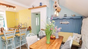 A cozy kitchen with yellow tiles, wooden furniture, and a dining area with a wooden table and chairs.