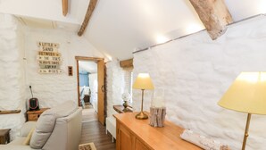 A cozy room with a sofa, wooden cabinet, and a lamp. There's a sign on the wall and a hallway leading to another room.