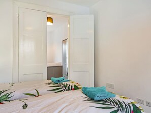 Ein Schlafzimmer mit zwei Betten, jeweils mit einem blumigen Überwurf und einem blauen Handtuch.