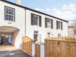 Ein weißes, zweistöckiges Haus mit überdachter Auffahrt und Holzzaun.