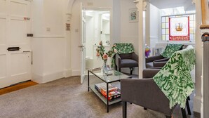 Una habitación con una mesa de centro de vidrio, dos sillones, un sofá y una puerta con un letrero.