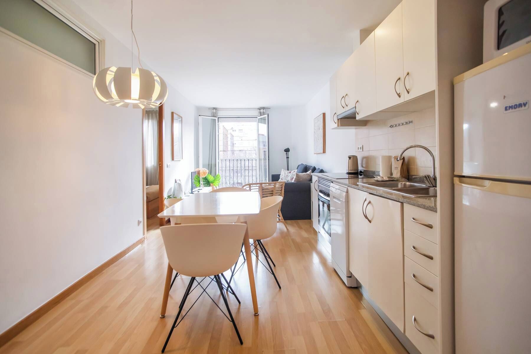 A modern kitchen with white cabinets, a built-in oven, and a stainless steel sink.